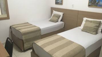 Quarto duplo com duas camas, uma escrivaninha e uma cadeira.