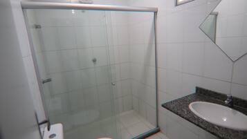 A bathroom with a glass shower enclosure, a toilet, and a sink with a granite countertop.