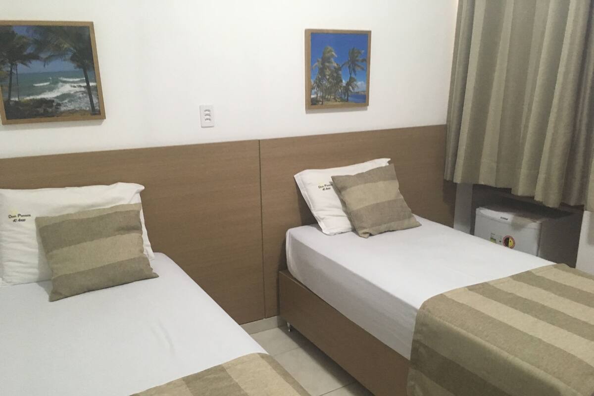 Two single beds with striped blankets, a headboard, and a small bedside table with a lamp.