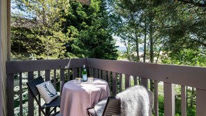 A deck with a table and chairs, a bottle of champagne, and a chair with a deer pillow. - Outpost: Sleeping Indian E8 - Hot Tub Access! (Teton Village)