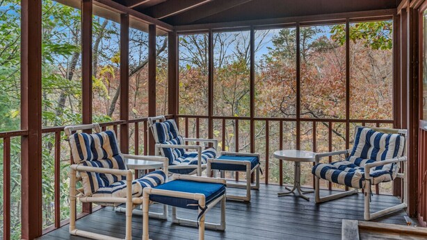 Un espacio de estar al aire libre con techo, muebles de madera y ventanas grandes.