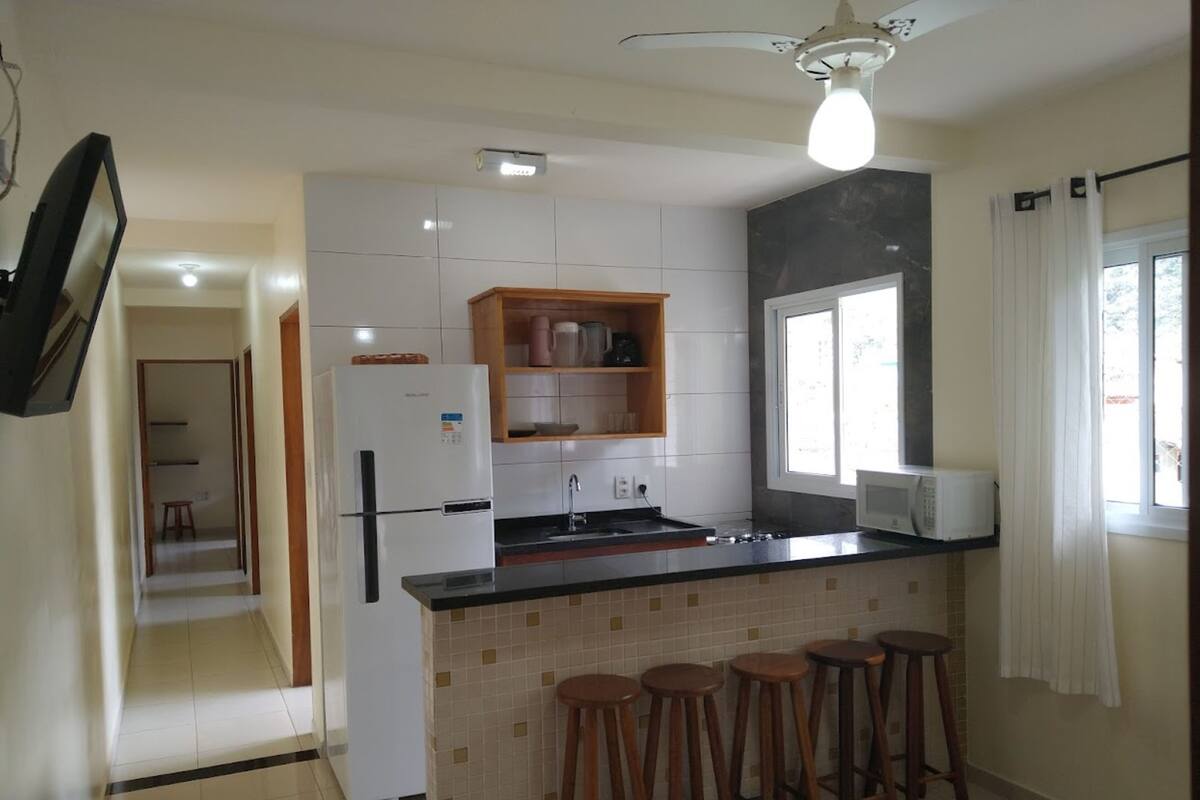 A kitchen with a refrigerator, microwave, and wooden stools.