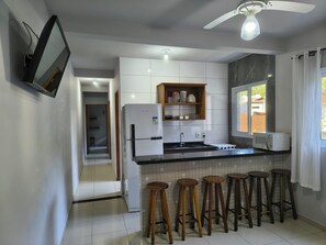 Una cocina moderna con refrigerador integrado, microondas y taburetes de madera.
