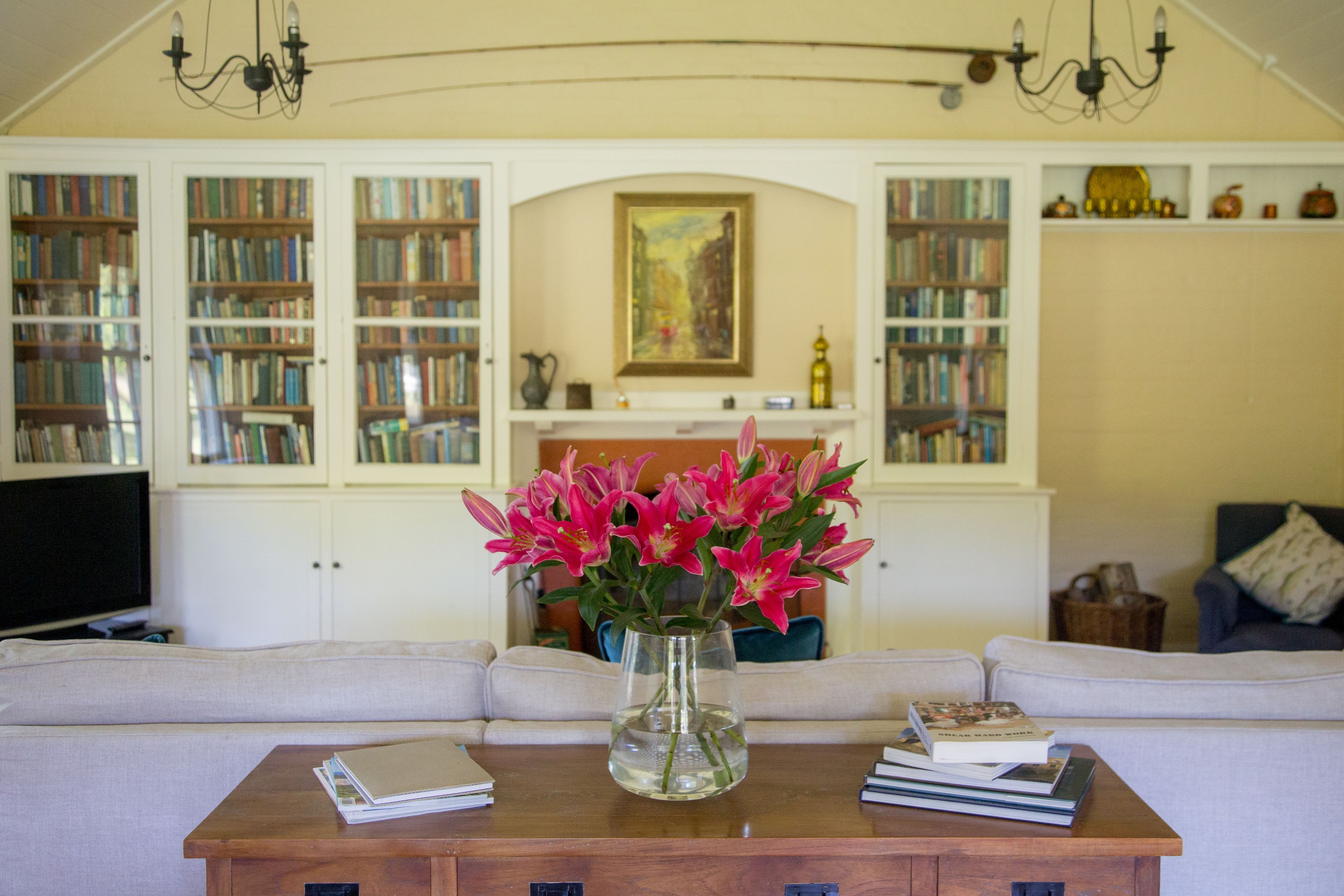 A living room with a bookshelf, a fireplace, and a vase with flowers on a coffee table.