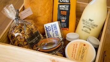 Una caja de madera con varios alimentos, como granola, mantequilla, jugo de naranja y productos lácteos.