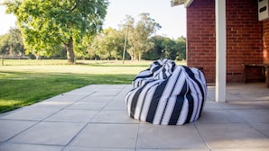 A striped bean bag chair on a patio with a brick building in the background. - Coldstream Estate - The Whare (Coldstream)