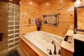 A wooden cabin bathroom with a large bathtub, a wooden vanity, and a mirror.