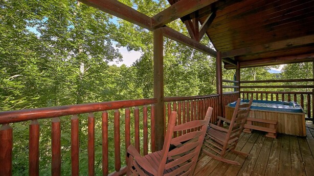 A wooden deck with a railing, a table, and chairs. - Natural Attractions Apartment 3 (Gatlinburg)