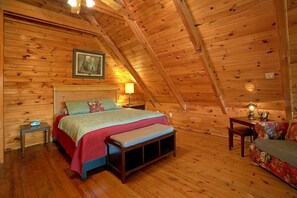 A cozy wooden cabin bedroom with a bed, bedside tables, a nightstand, a bench, and a chair. - Moonshiners View Apartment 2 (Gatlinburg)