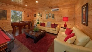 A cozy cabin interior with a foosball table, a sofa, a coffee table, and a red lamp. - Tranquility Apartment 2 (Sevierville)