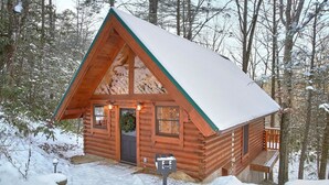 A log cabin with a snow-covered roof, a front door, and a porch. - Foolin Around Apartment 1 (Sevierville)