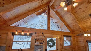 A log cabin interior with a sloped ceiling, wooden walls, and large windows. - Foolin Around Apartment 1 (Sevierville)