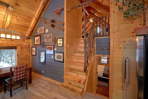 Cozy cabin with a wooden staircase, dining area, and framed wildlife photographs.