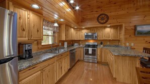 A modern kitchen with wooden cabinets, stainless steel appliances, granite countertops, and a central island.