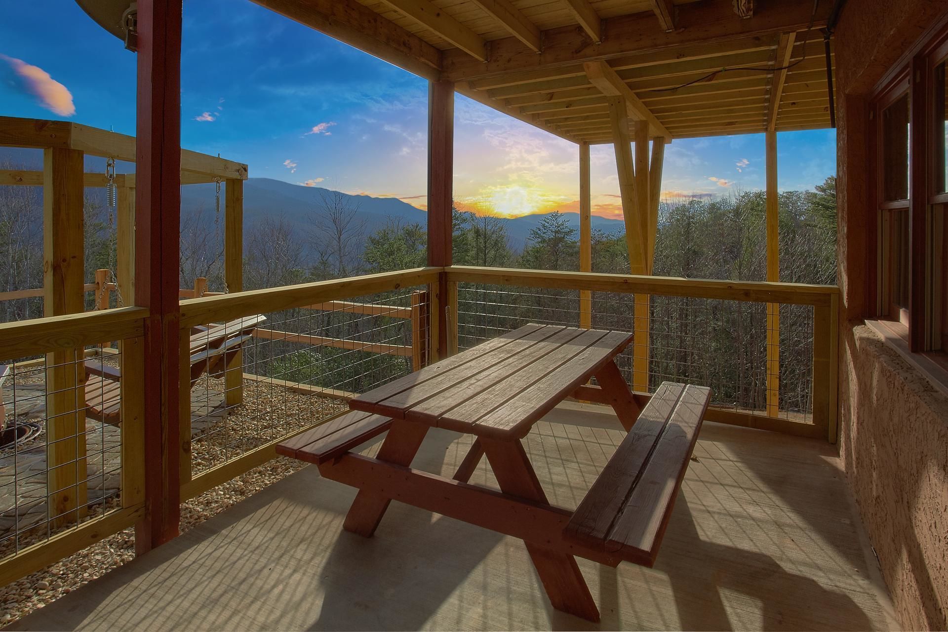A wooden deck with picnic tables and a view of mountains.