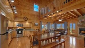 A spacious log cabin interior with a kitchen, dining area, and living room.