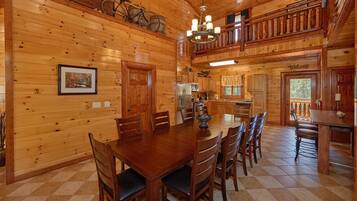 A wooden cabin interior with a dining area, kitchen, and a balcony.