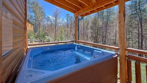 A hot tub in a wooden cabin with a view of a forest. - Sweet Tranquility Pool Lodge Apartment 4 (Cosby)