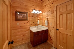 A wooden-paneled bathroom with a sink, mirror, and towel rack. - A Smoky Hideaway Apartment 5 (Gatlinburg)