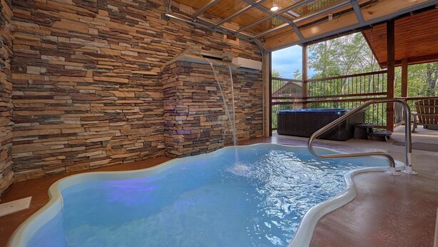 An indoor swimming pool with stone walls and a view of the outdoors. - Big Sky Lodge Apartment 2 (Gatlinburg)