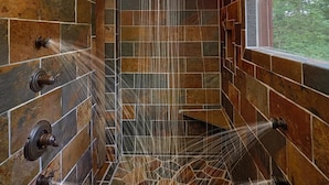 A shower with multiple nozzles, a wooden ceiling, and a stone wall. - Big Sky Lodge Apartment 2 (Gatlinburg)