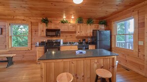 Cocina de cabaña de madera con una isla central, taburetes de bar y electrodomésticos integrados.