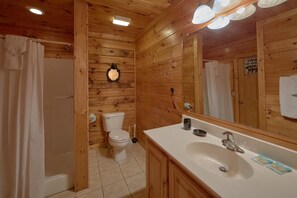 A wooden cabin bathroom with a toilet, sink, and shower.