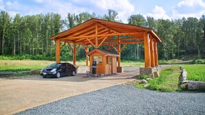 A wooden cabin with a covered porch, a car parked in front, and a forested background. - Pool Movie 1 Apartment 6 (Cosby)