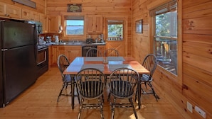 Una cocina estilo cabaña con paredes de madera y una amplia mesa de comedor.