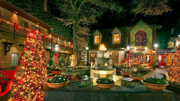 A courtyard with a large Christmas tree, a fountain, and a building with a green roof and a sign that reads "The Cheese Shop." - Forever Young Apartment 2 (Gatlinburg)