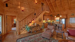 A wooden cabin interior with a staircase, kitchen, dining area, and living room. - Time Stands Still Apartment 3 (Sevierville)