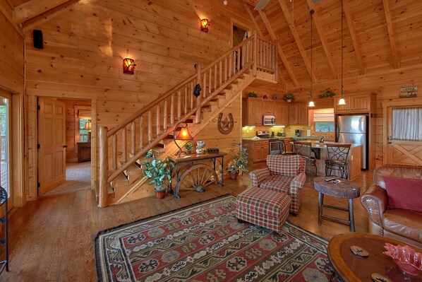A wooden cabin interior with a staircase, kitchen, dining area, and living room. - Time Stands Still Apartment 3 (Sevierville)