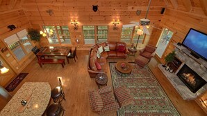 A cozy log cabin interior with a fireplace, leather furniture, and a television. - Time Stands Still Apartment 3 (Sevierville)