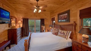 A wooden cabin bedroom with a bed, dresser, and a ceiling fan. - Time Stands Still Apartment 3 (Sevierville)
