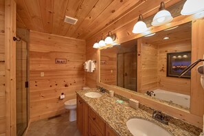A wooden cabin bathroom with a granite countertop, two sinks, a large mirror, and a shower. - Time Stands Still Apartment 3 (Sevierville)