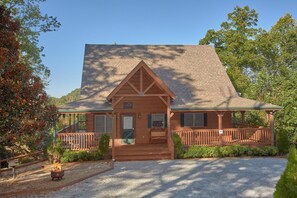 A cabin with a steeply pitched roof, a covered porch, and a gravel driveway. - Time Stands Still Apartment 3 (Sevierville)