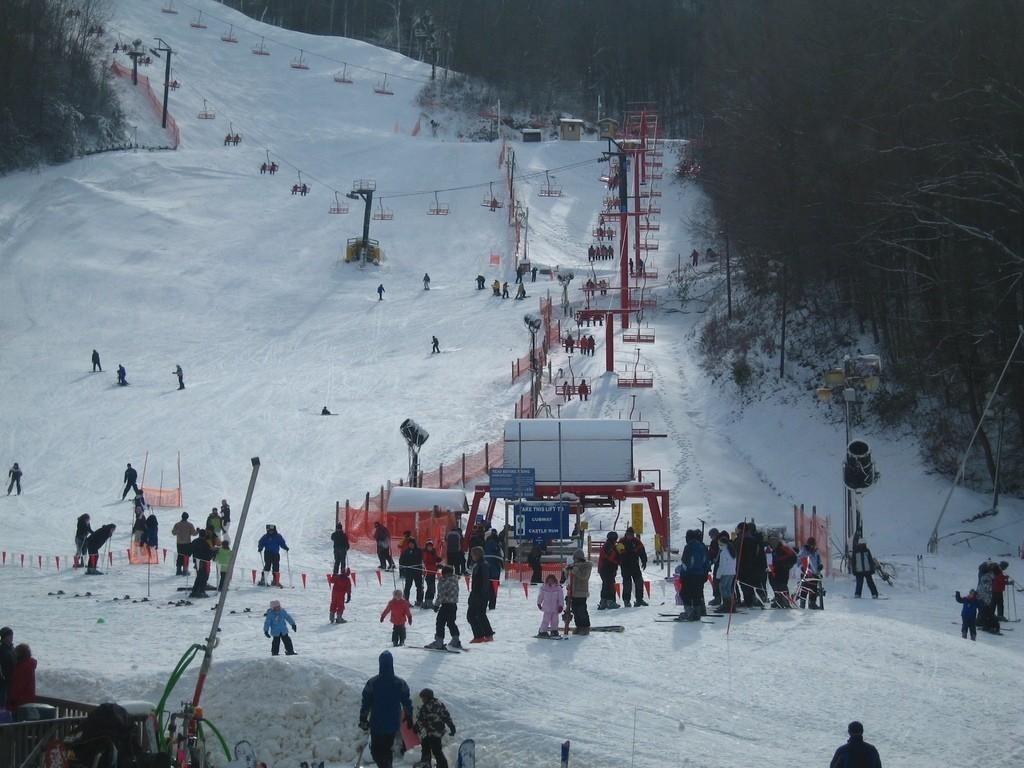 A ski slope with a ski lift and people skiing.
