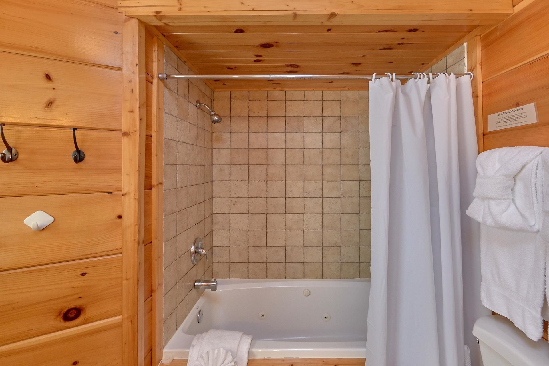 A wooden cabin bathroom with a bathtub, a shower, and a towel rack.