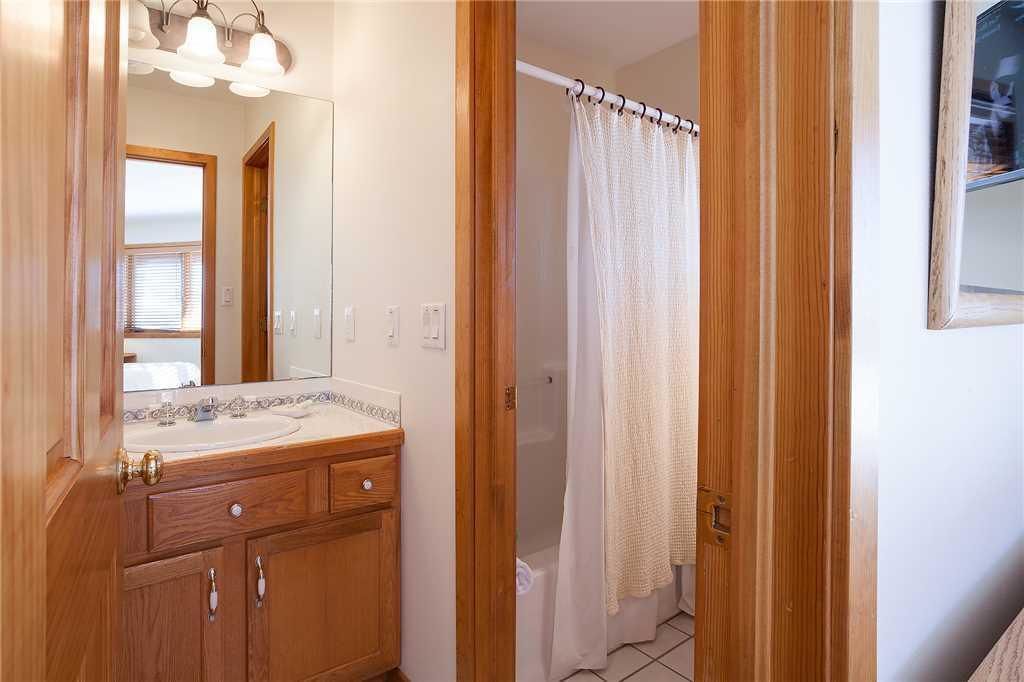 A bathroom with wooden cabinets, a sink with a mirror, and a shower curtain.