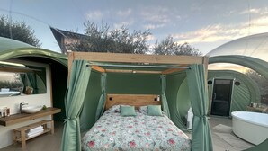 Alojamiento en tienda de campaña con cama, lavamanos y zona de ducha.