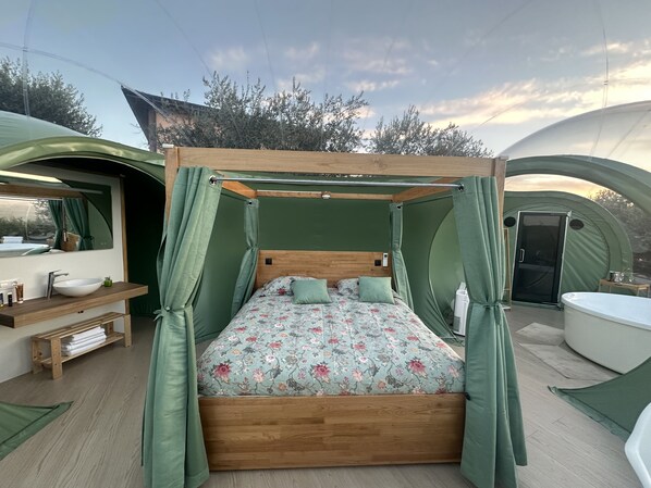 Alojamiento en tienda de campaña con cama, lavamanos y zona de ducha.
