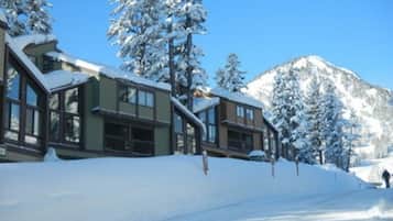 A snow-covered mountain lodge with large windows and a prominent staircase.