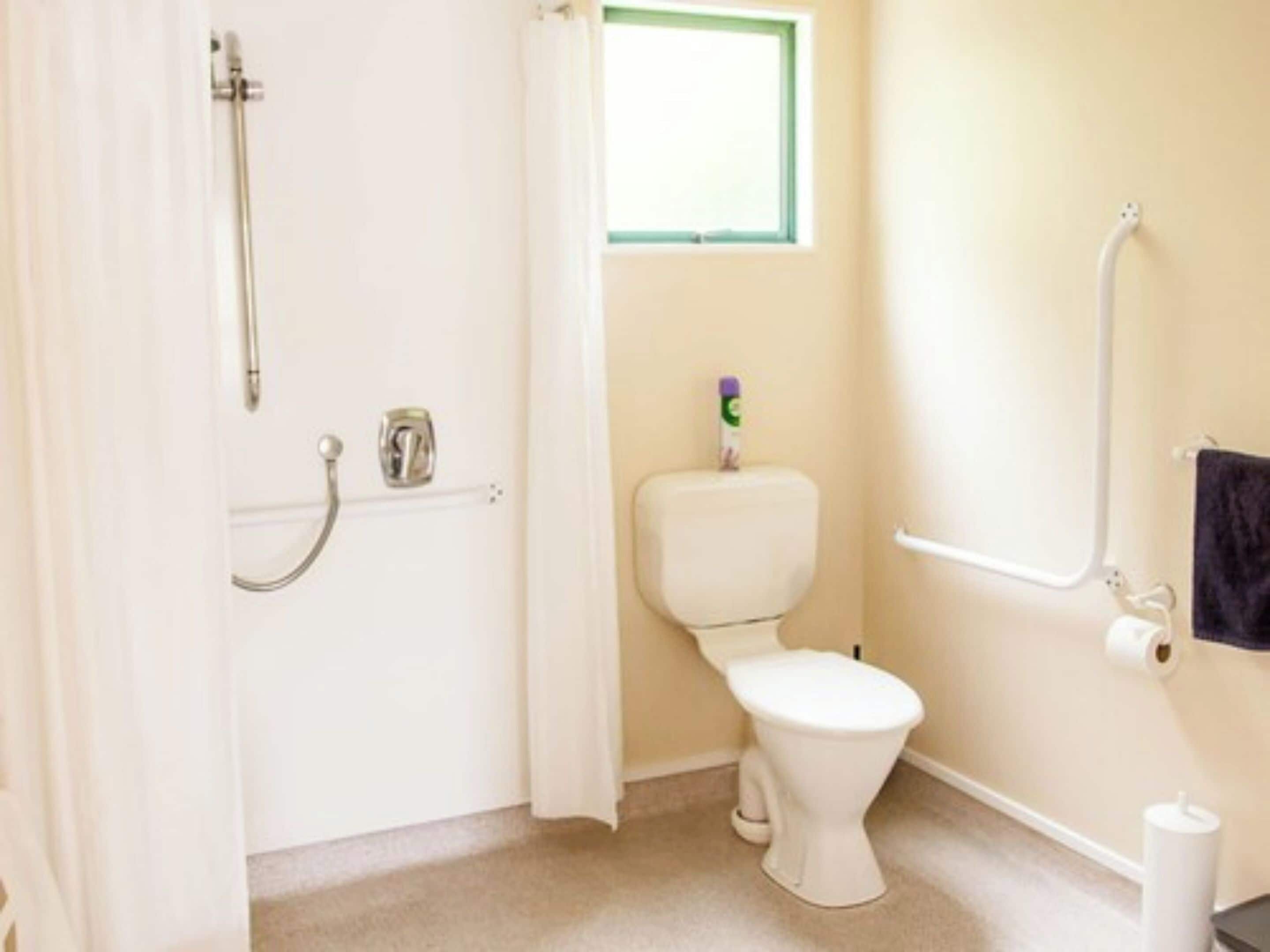 Une petite salle de bain avec des toilettes, une douche et une fenêtre.