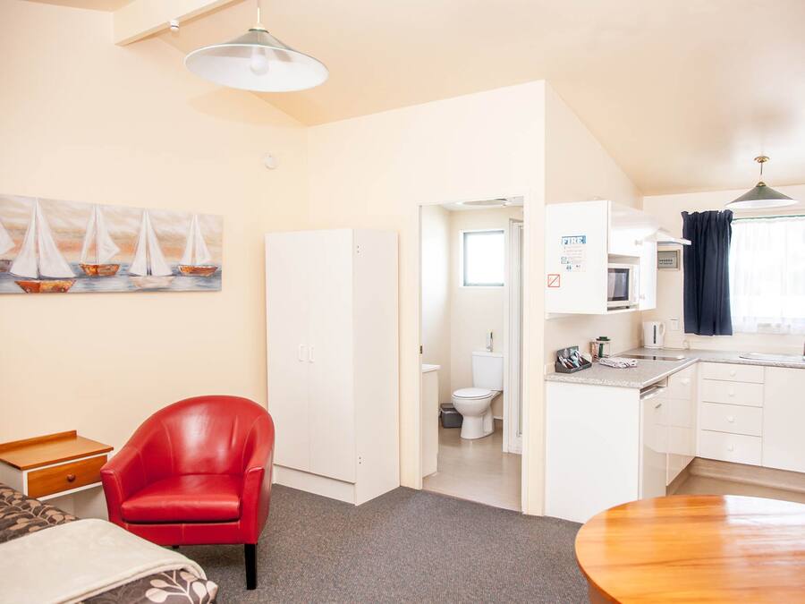 A compact living space with a kitchenette, a dining area, and a bathroom.
