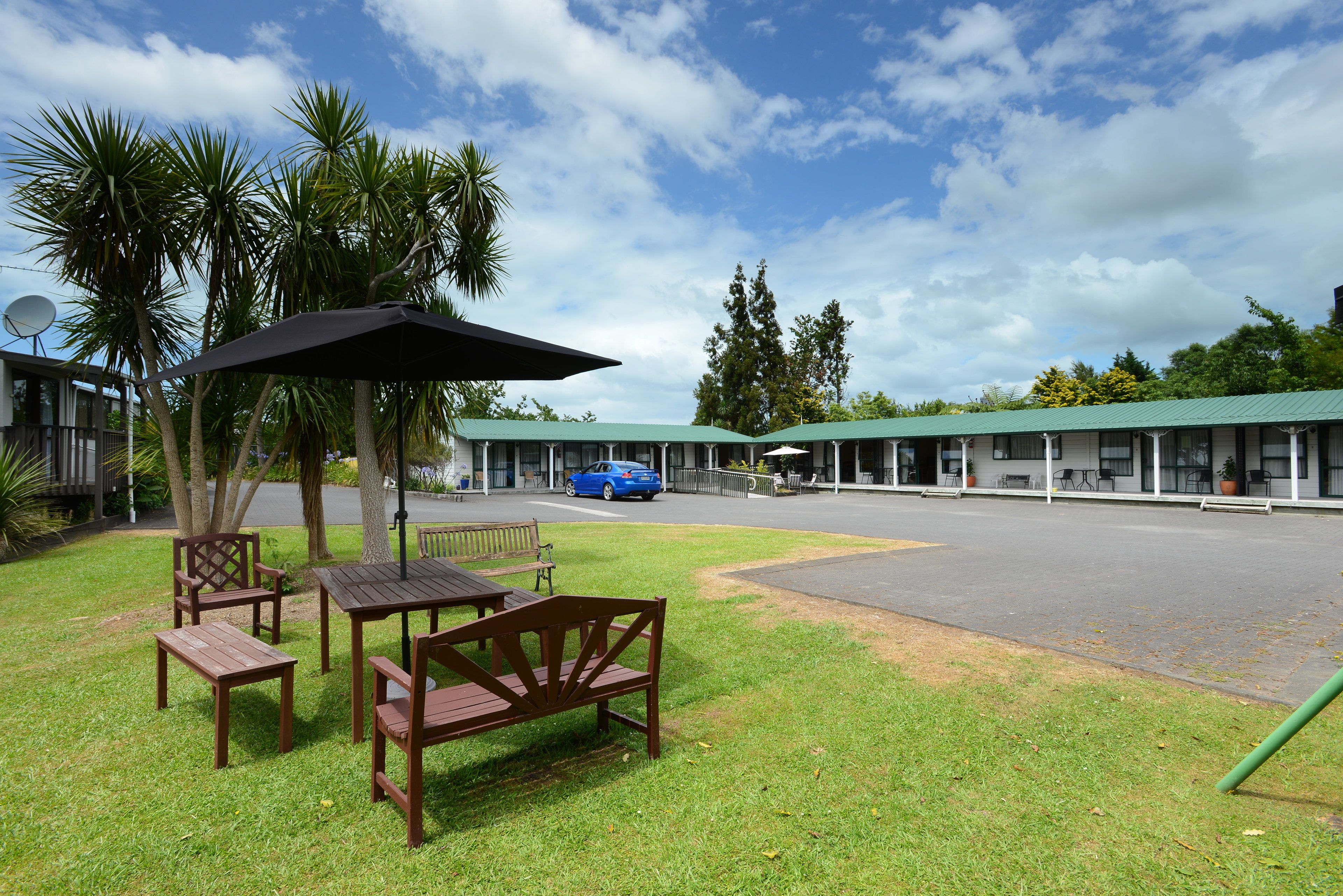 Un motel con área de estar al aire libre, zona techada y estacionamiento.