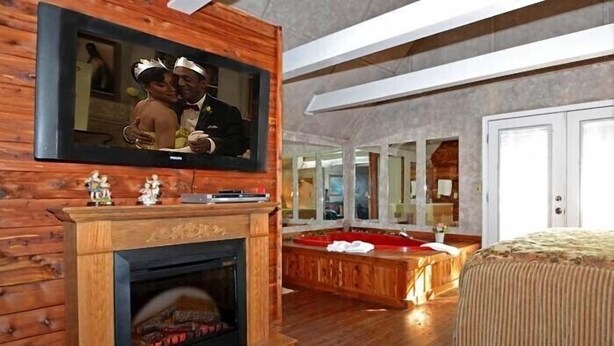 Ein Zimmer mit Kamin, einem großen Spiegel, einer hölzernen Bank und einem Bett.