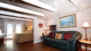 Ein geräumiges Wohnzimmer mit einer großen schwarzen Ledersofa, einem Bild an der Wand und einem Deckenventilator.