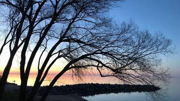 Vista di un lago al tramonto, con una banchina alberata.
