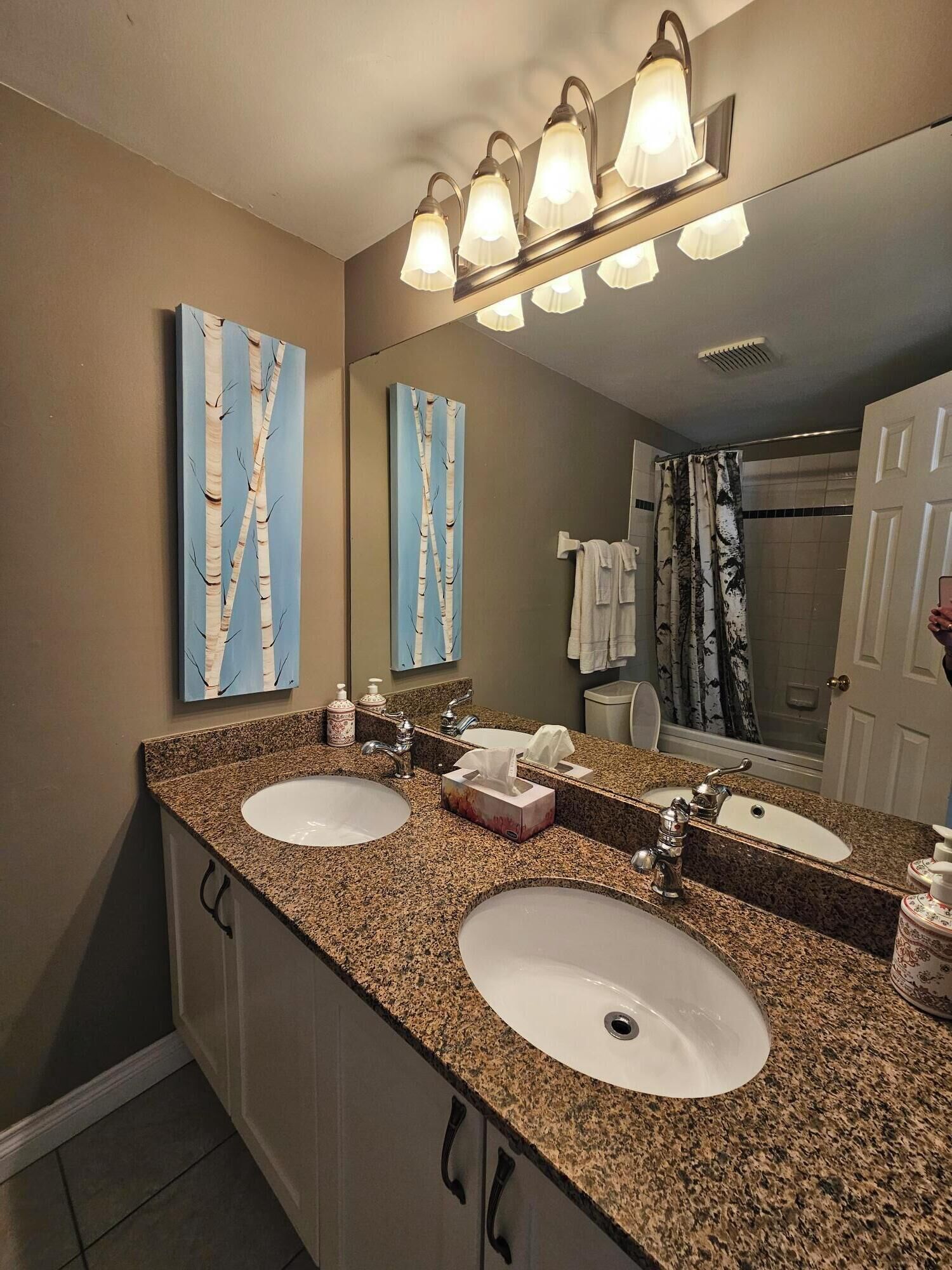 A bathroom with two sinks, a mirror, and a shower.