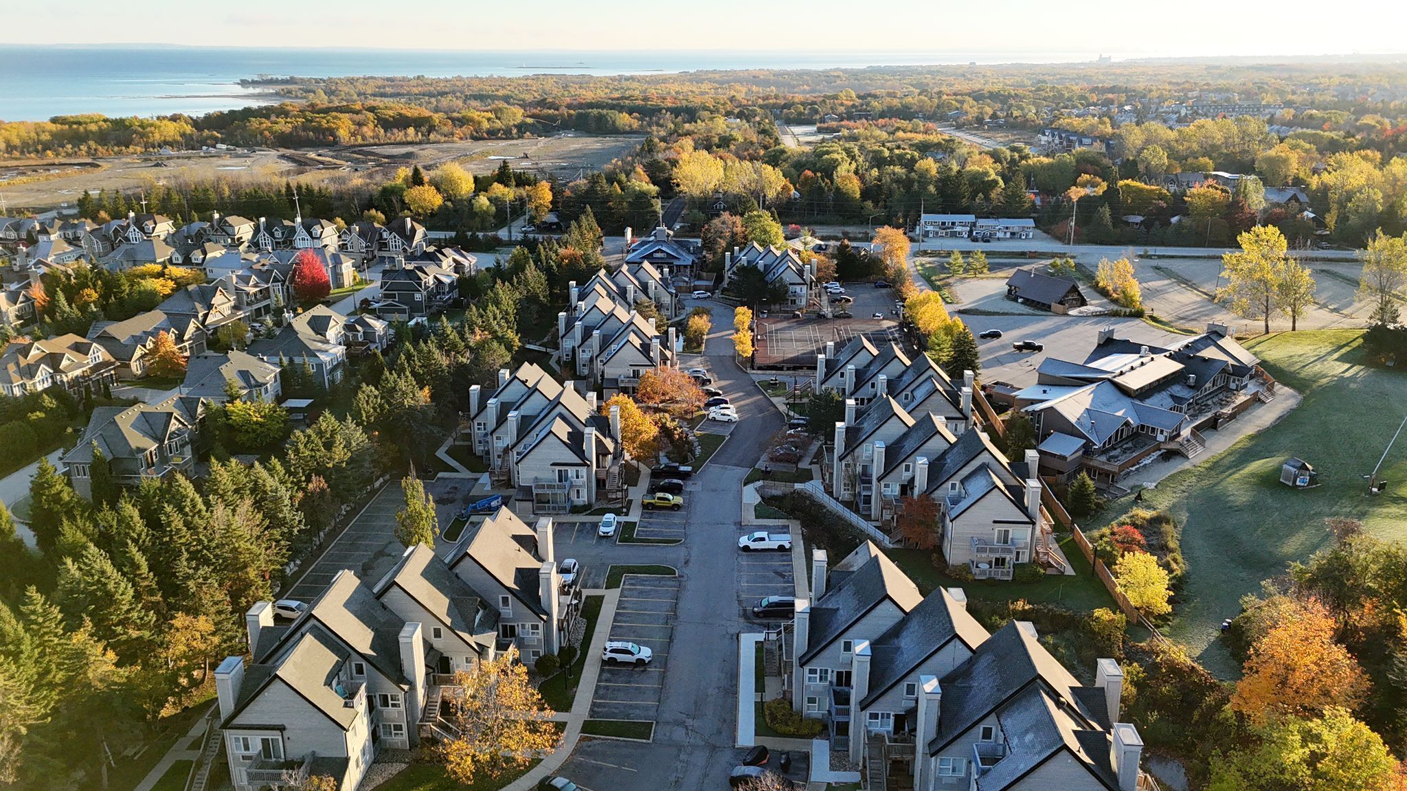 Une vue aérienne d’un quartier résidentiel, avec des maisons, des routes et une étendue d’eau en arrière-plan.